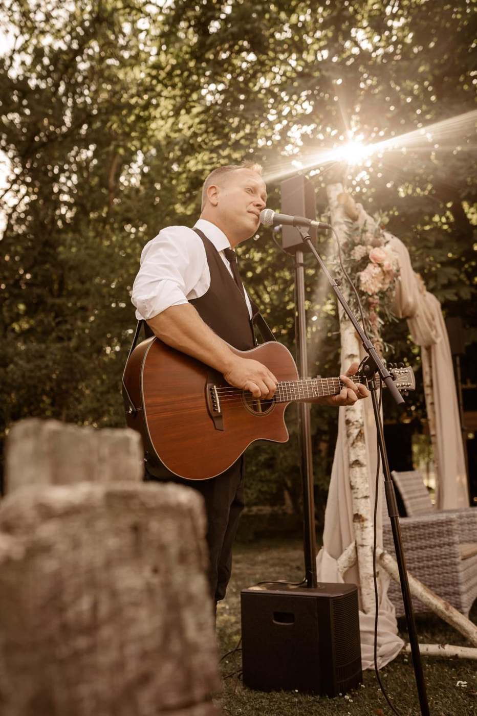 John Eid spielt Gitarre bei einer Trauung im goldenen Abendlicht vor Birken