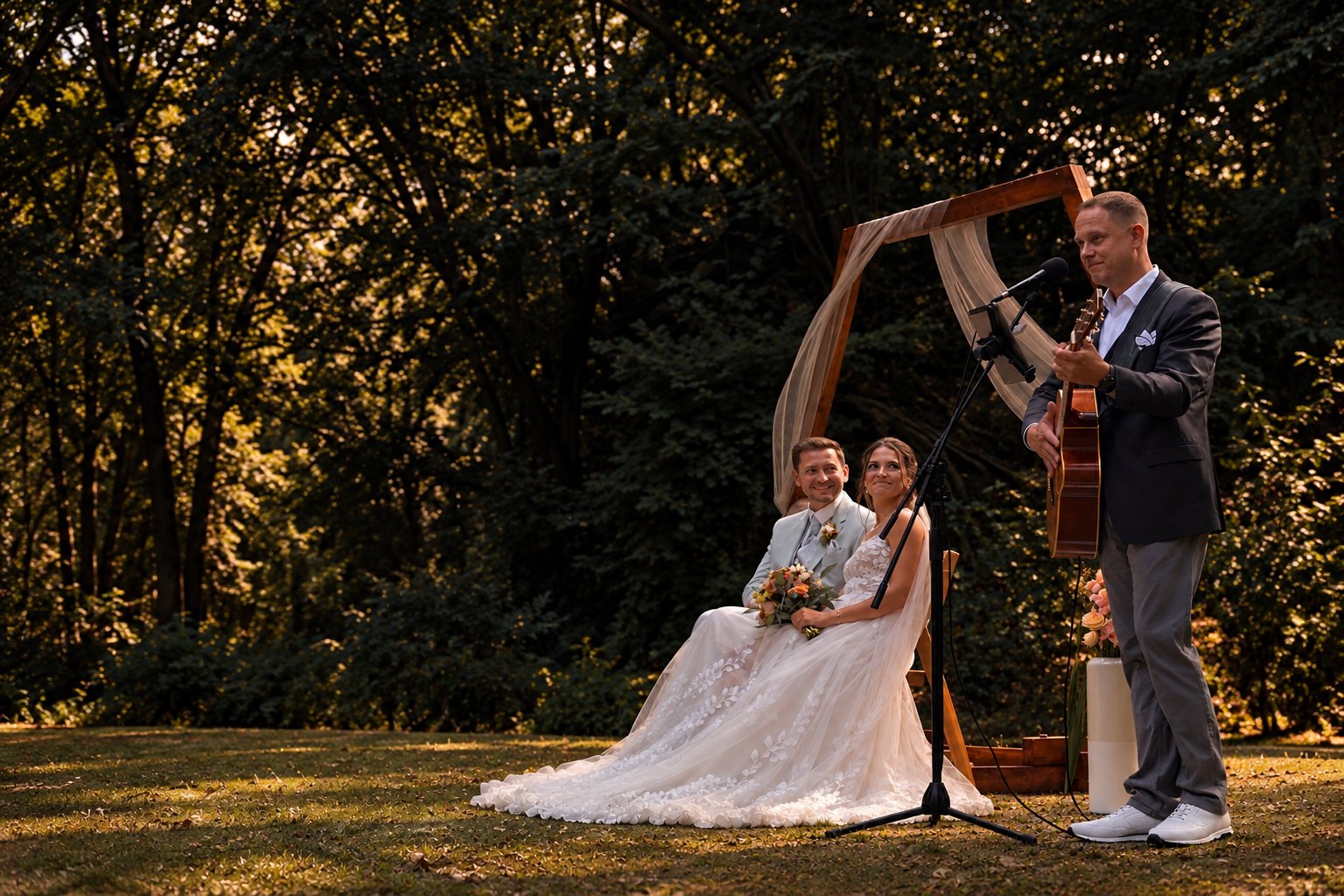 John Eid singt und spielt Gitarre bei einer freien Trauung im Freien, das Brautpaar sitzt daneben und lächelt